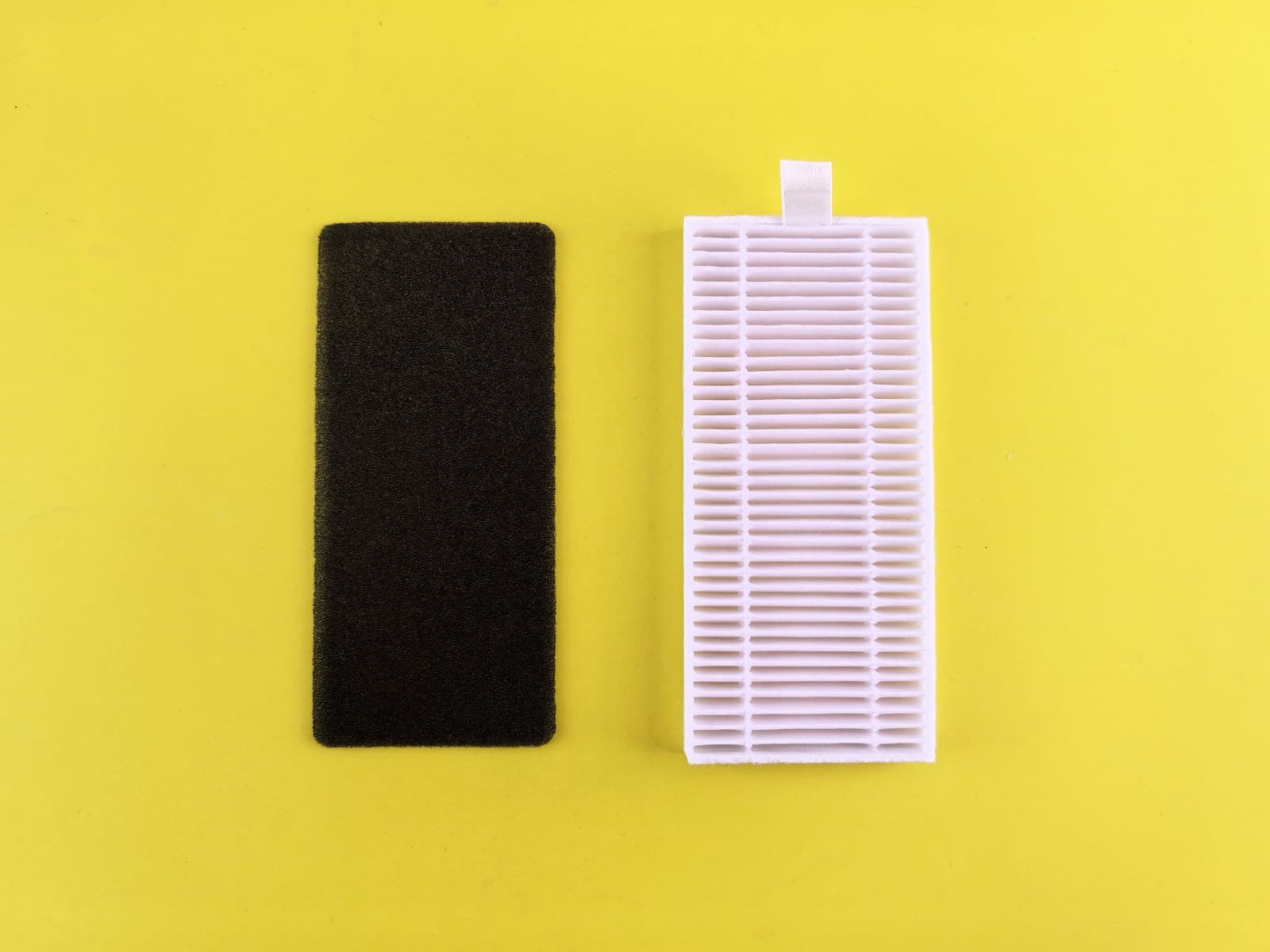 A clogged dark filter beside a clean white pleated filter